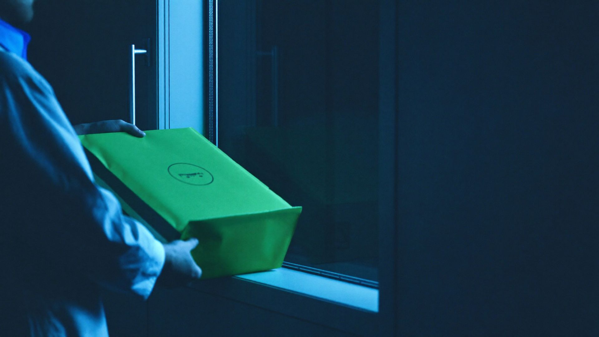 Laboratory receiving window at night, technician accepting a sealed transport tote